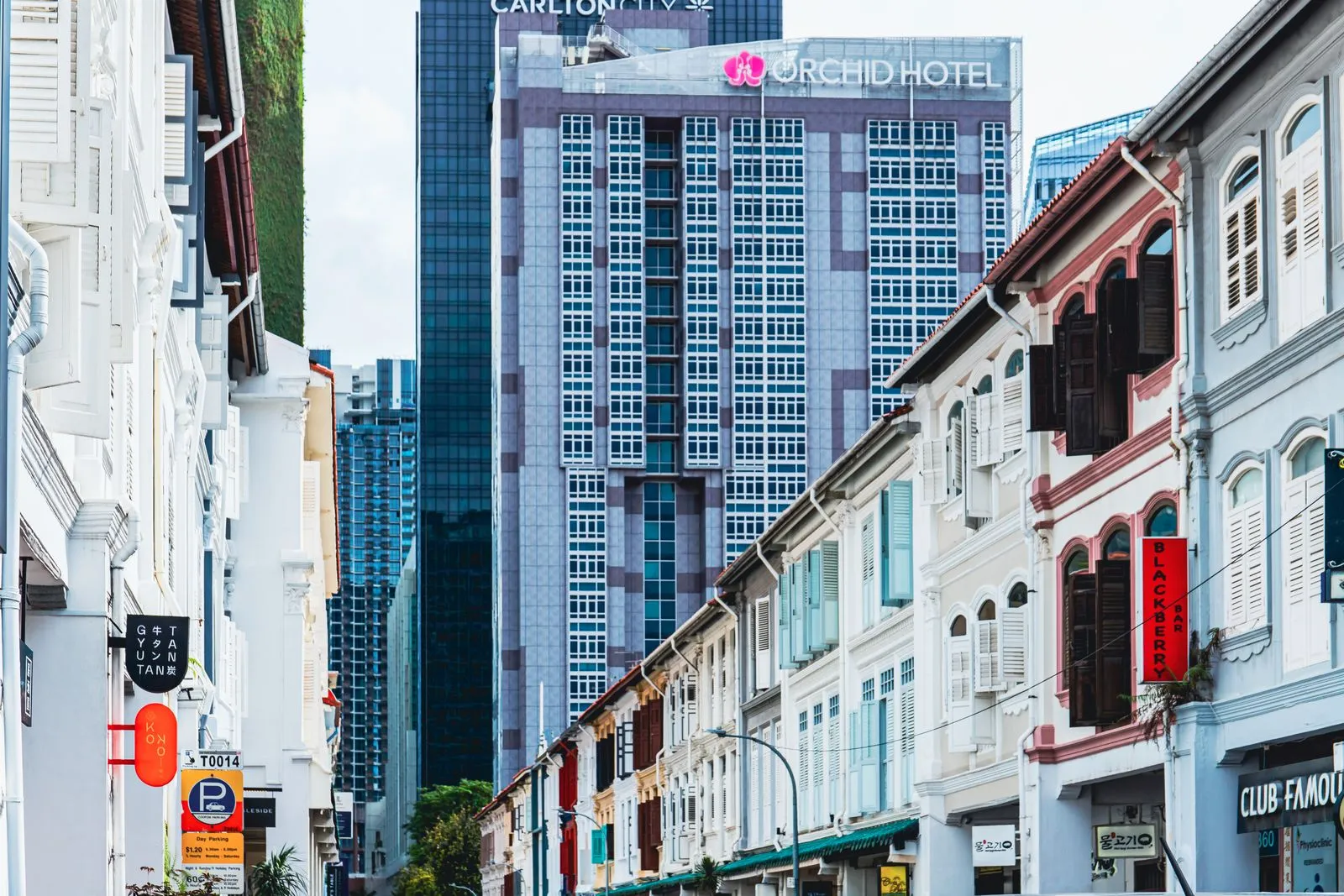 Shophouses on a Singapore street with the towers of the central business district behind them.