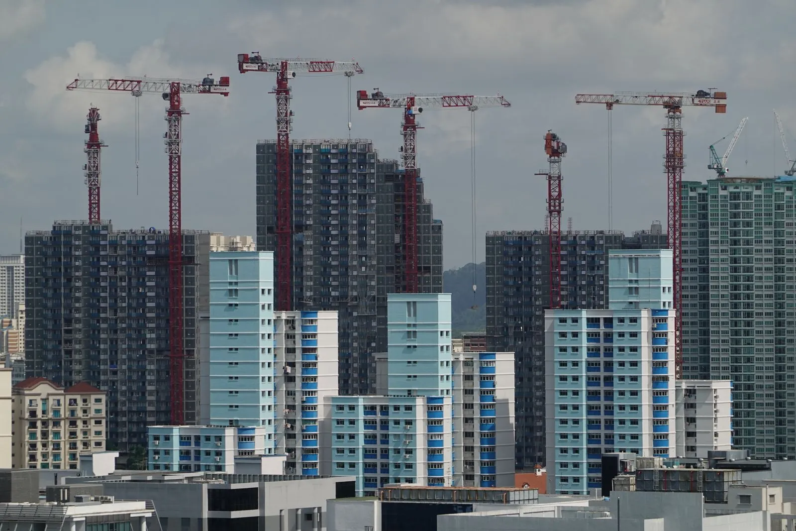 Tower cranes over residential blocks under construction in Singapore.