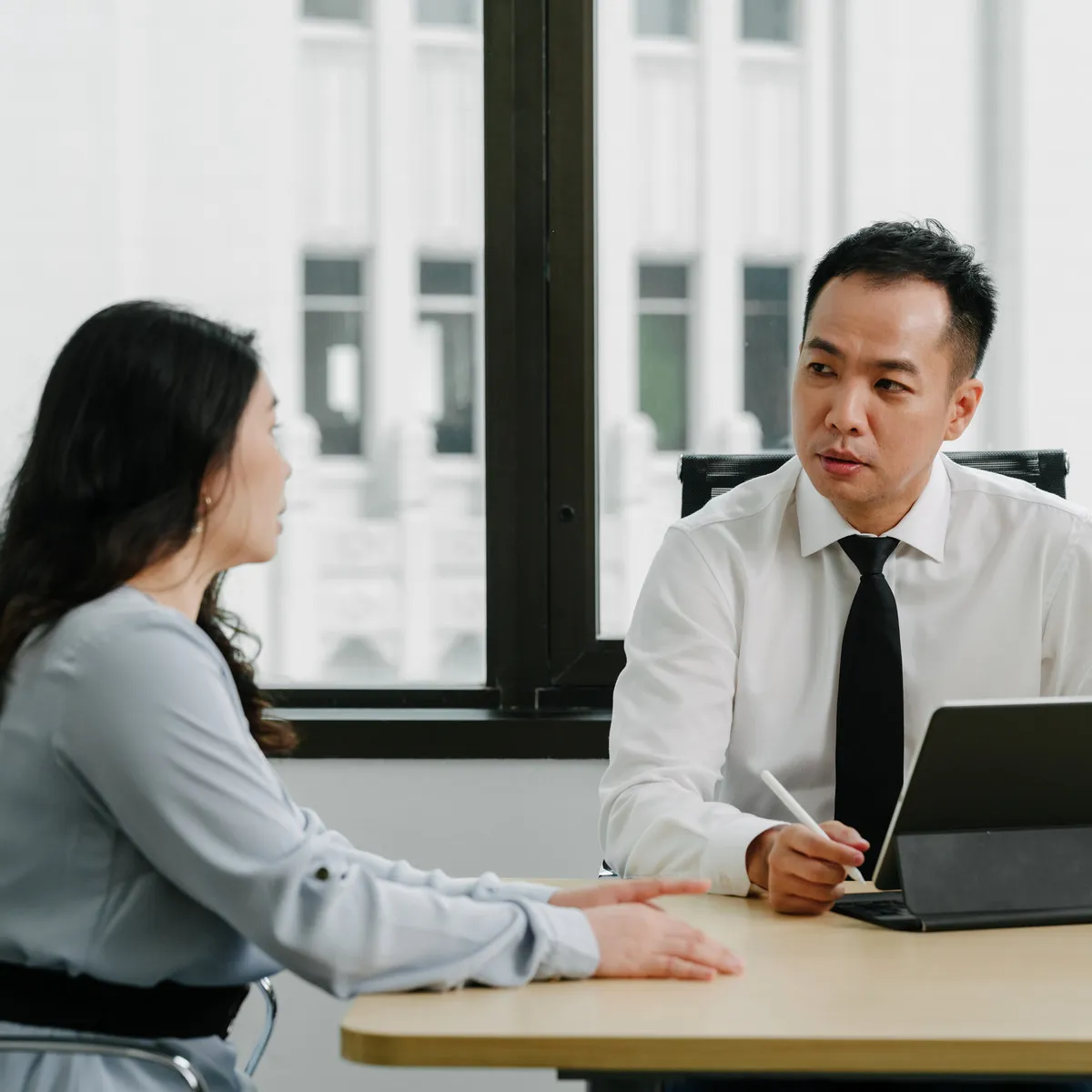 A JCP Law lawyer and a client in conversation at a meeting room table.