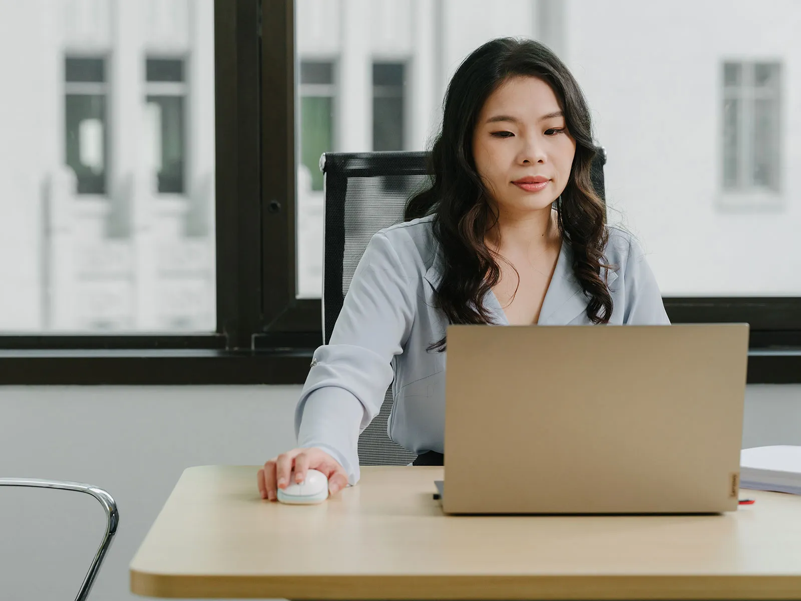 A woman working at a laptop in a bright Singapore office.