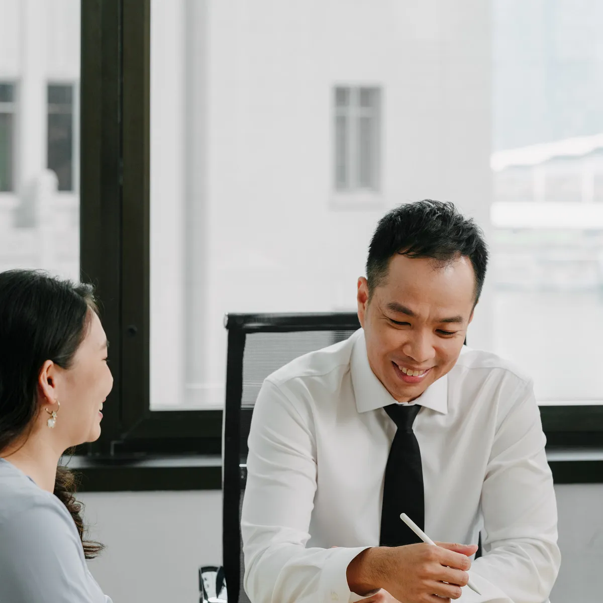 A JCP Law lawyer and a client talking across a meeting room table, both smiling.