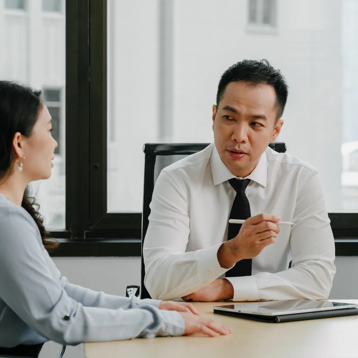 A JCP Law lawyer explaining a point to a client across a meeting room table.