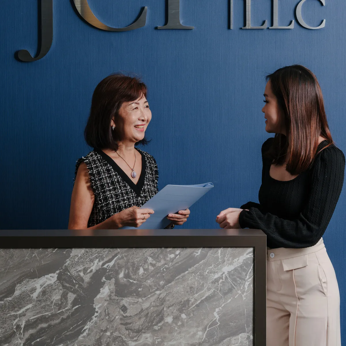 A client handing documents across the reception desk at JCP Law LLC.