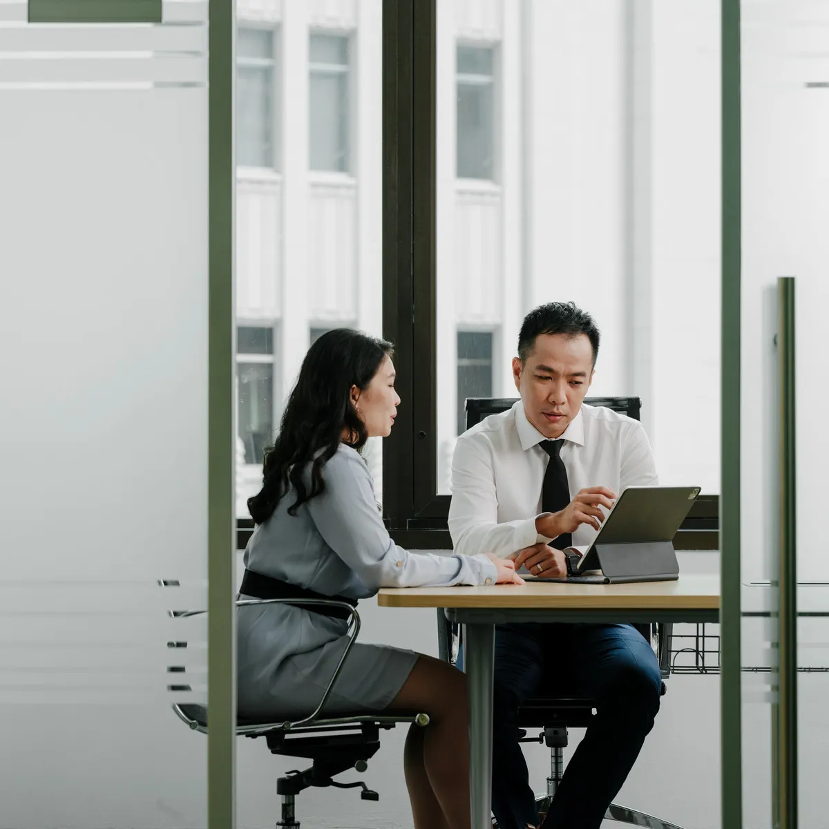 A JCP Law lawyer and a client reviewing a document on a tablet in the firm's meeting room.