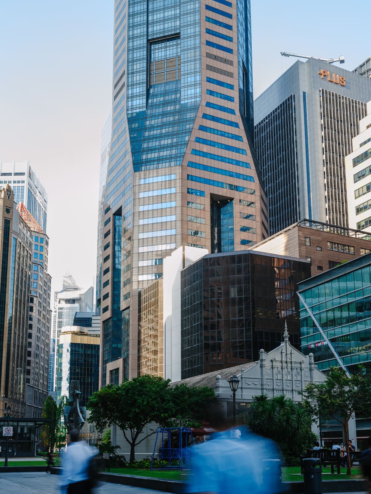 Looking up at Six Battery Road in Raffles Place, where JCP Law LLC is based; passersby blur past the tower in the foreground.
